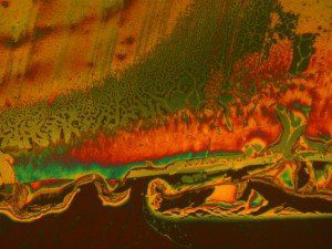 Faulty optical coating testing - Nomarski phase interference contrast microscopy used to detect areas damaged by a cleaning chemical on the anti-reflective coating on a high value lens element.