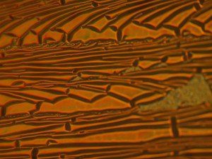 Delamination Testing - Delamination of an optical coating occurred when it was subjected to a low-adhesion tape pull test. The optical coating could not be seen on the tape by the naked eye, but with the use of the Nomarski phase interference contrast microscopy, it was easily visible, as were the size and elongation of grains in the film and the completeness of the film failure.