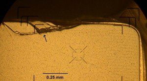 A fractured edge (shown by arrow) of a green ceramic capacitor as a result of its mishandling during soldering assembly.